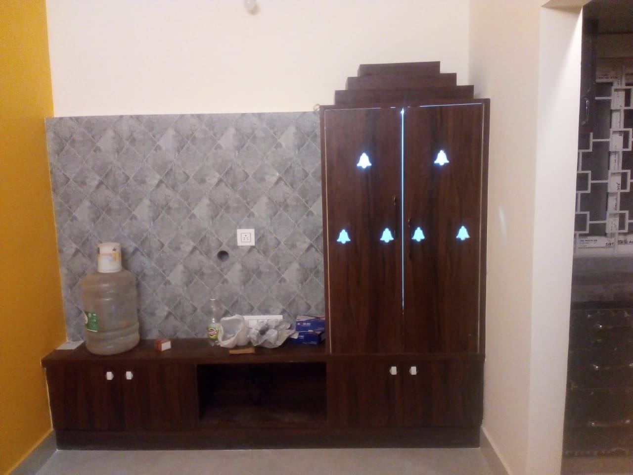 Walnut console with a tall pooja cabinet lit through bell-shaped cut-outs