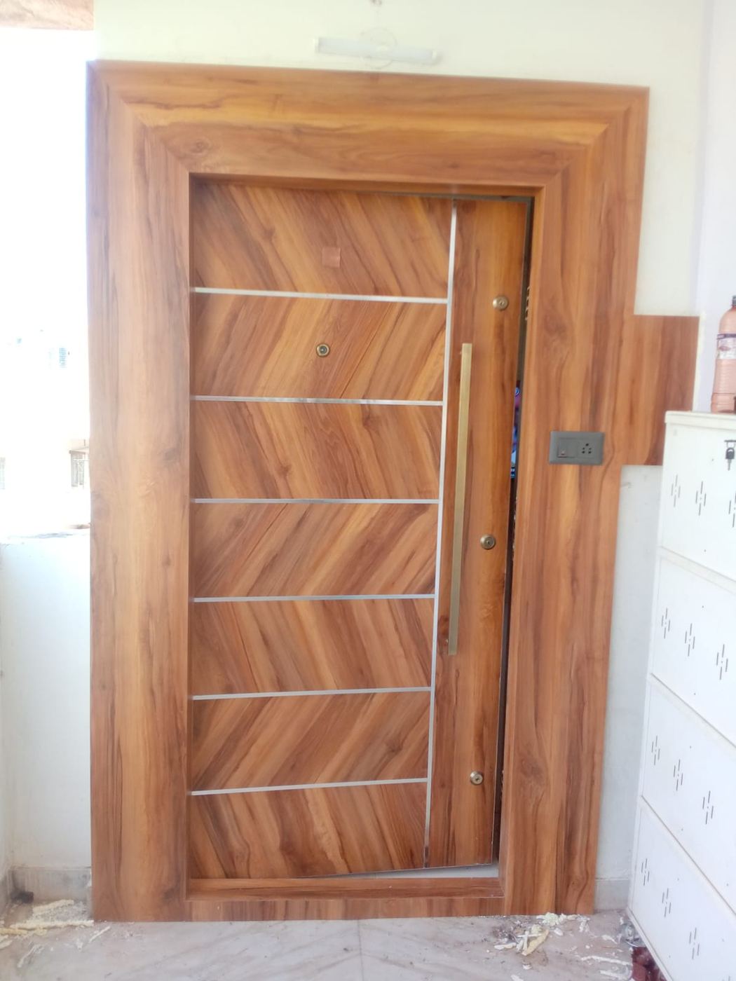Flush door in figured teak laminate with horizontal stainless inlay strips