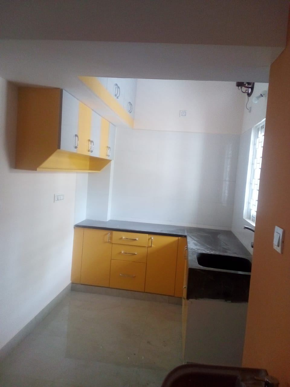 Compact yellow and white modular kitchen with granite counter and sink