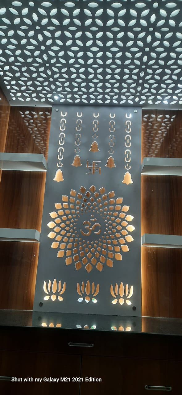 Close view of the backlit cut-out pooja panel and the perforated false ceiling above