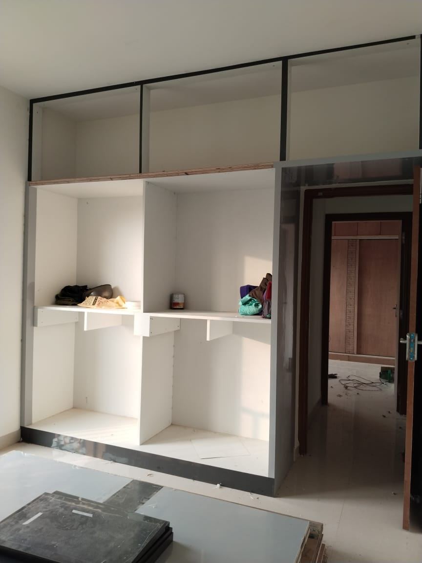 White storage carcass with open shelves and loft framing, before shutters