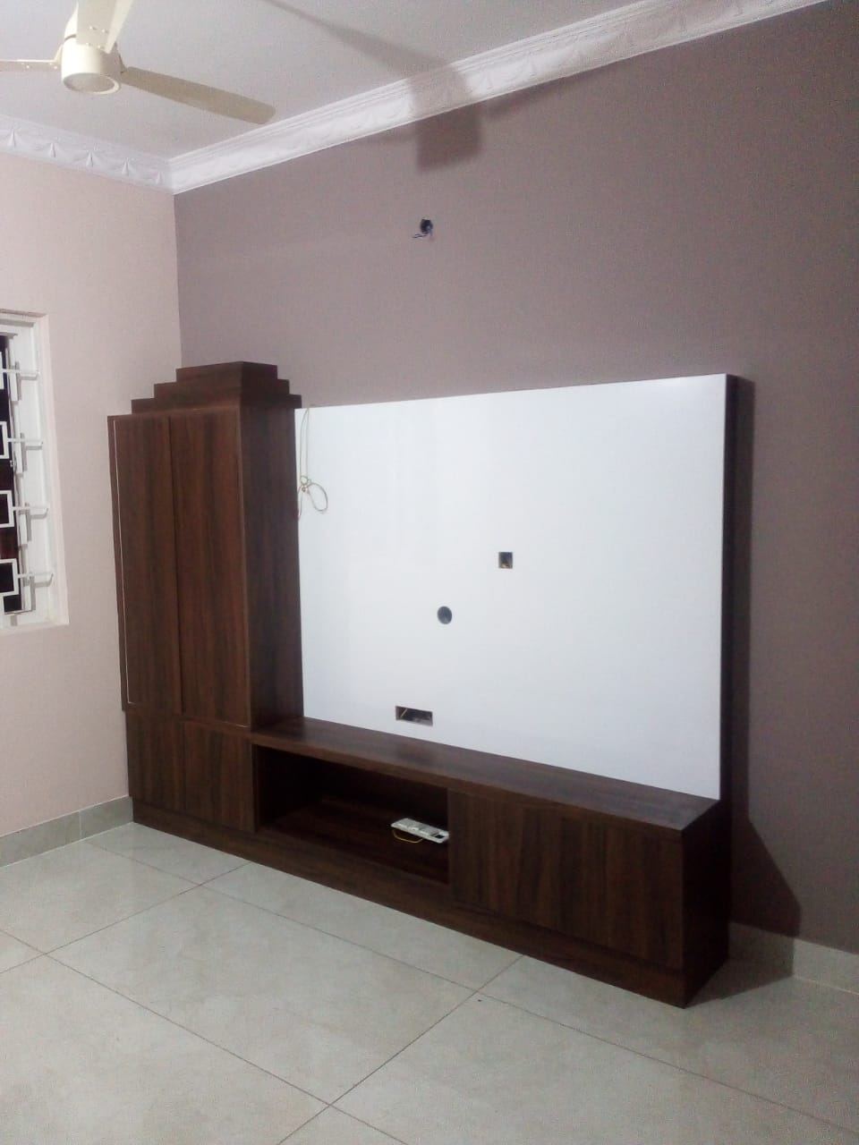 Media wall with a white lacquered panel and a stepped walnut tall cabinet
