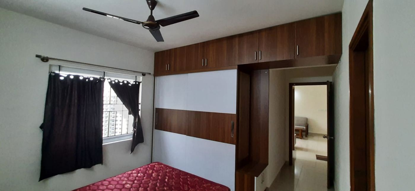Furnished bedroom with a full-width wardrobe in walnut and white laminate and loft units above