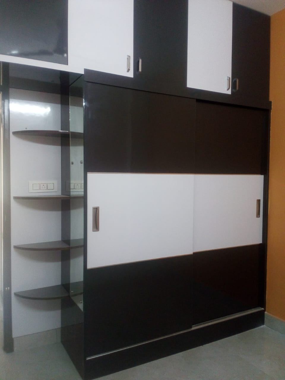 High-gloss dark and white sliding wardrobe with glass corner shelving