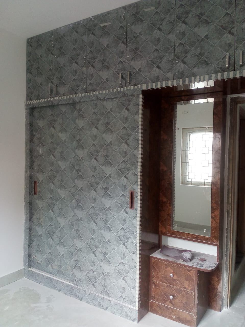 Wide view of the textured laminate wardrobe run with dresser and mirror