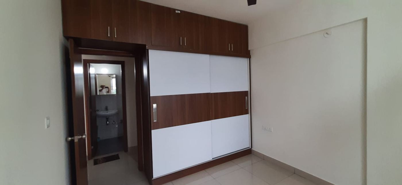 Walnut and white sliding wardrobe with loft, beside a bathroom door