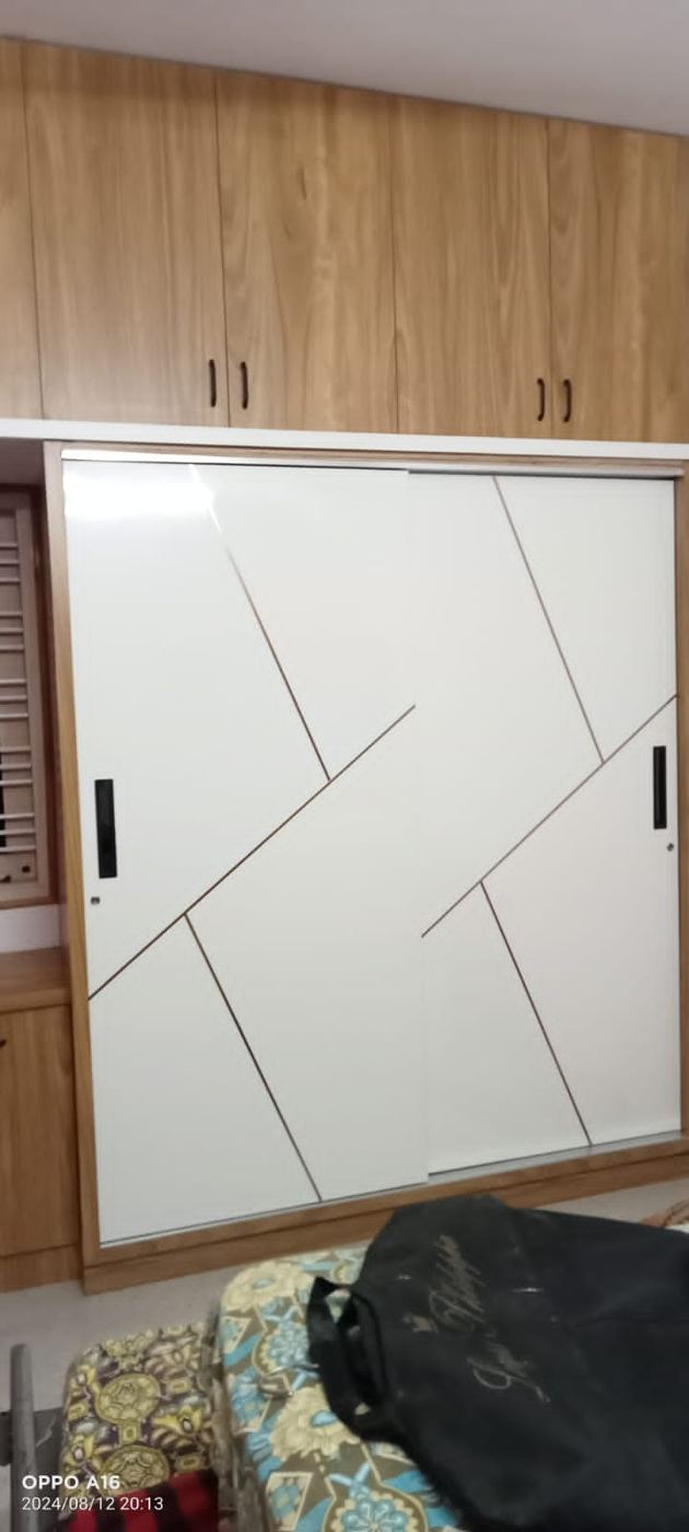 White gloss sliding wardrobe with an angled copper inlay pattern and teak loft above